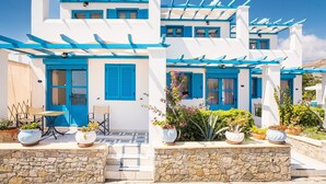 A white building with blue shutters and a stone wall. - Holiday Home 'Livadia Beach Tilos Apartment ' with Sea View, Wi-Fi and Air Conditioning (tilos)