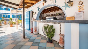 Un bar situé en bord de mer, avec un sol à carreaux, un comptoir doté d’une vitrine et des éléments décoratifs tels que des étoiles de mer et une lanterne.
