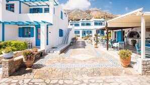 Un bâtiment traditionnel de couleur blanche, agrémenté de touches de bleu, avec une cour pavée de pierres et des espaces de repos en plein air.