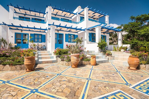 A white building with blue accents, terracotta planters, and a tiled patio.
