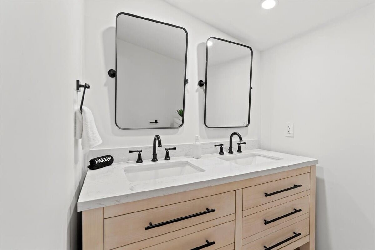 A modern bathroom with two sinks, a vanity with drawers, and two wall-mounted mirrors.