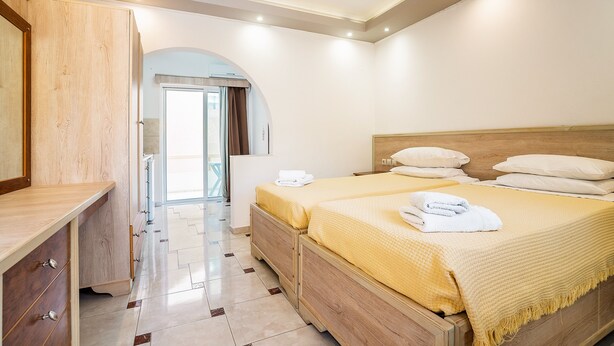 A bedroom with a wooden bed, a bedside table, and a view of the outside. - Holiday Home 'Olympus Tilos Apt Twin A3 ' with Mountain View, Wi-Fi and Air Conditioning (Tilos)