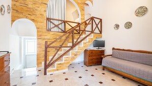 Ein Zimmer mit einer Holztreppe, einem Sofa, einem Fernseher und dekorativen Tellern an der Wand.