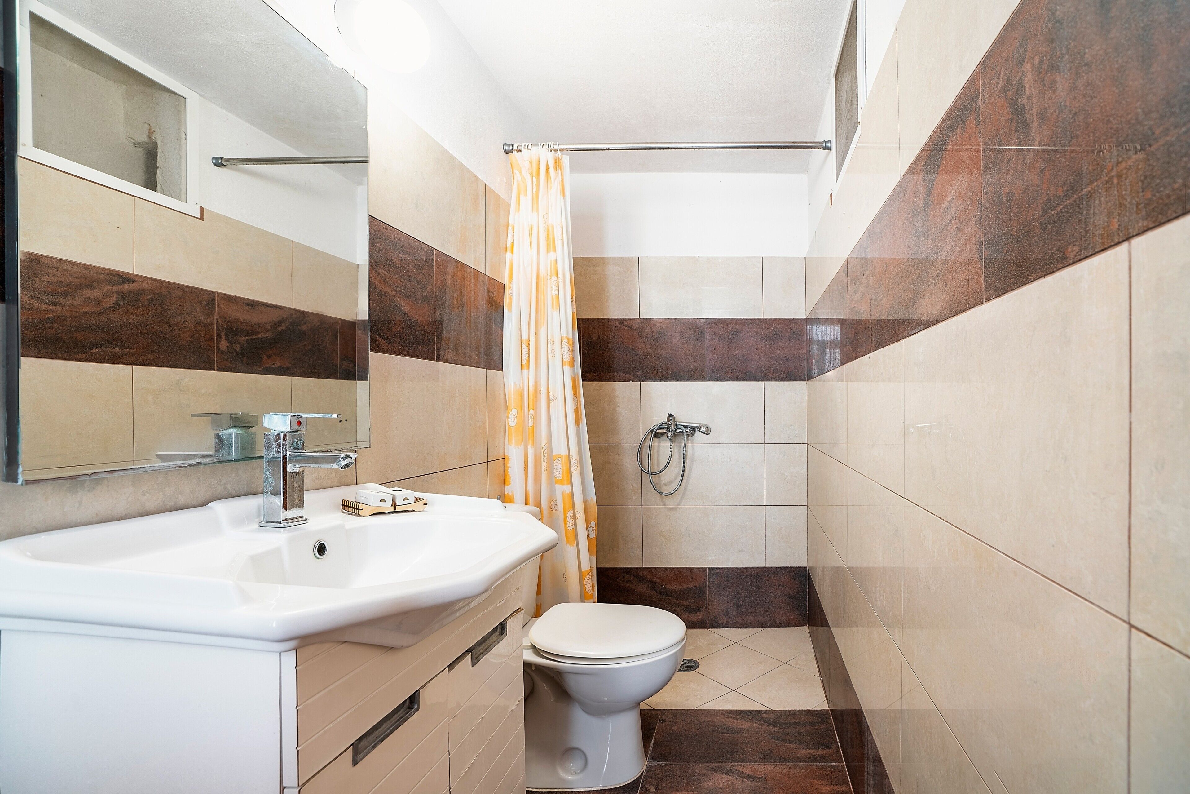 Een badkamer met een wastafel, toilet, douche en spiegel.