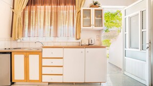 A kitchen with wooden cabinets, a countertop, and a window with curtains.