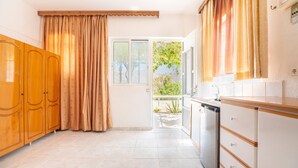 A kitchen with wooden cabinets, a dishwasher, and a window with curtains.