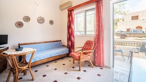 Una habitación con sofá, sillón, mesa y ventana con cortinas.