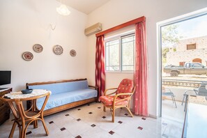 A room with a sofa, a chair, a table, and a window with curtains.
