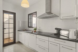 A modern kitchen with white cabinets, a black countertop, a built-in stove, and a coffee maker.