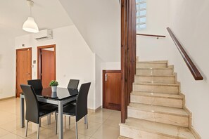 Un intérieur moderne comprenant un coin repas, un escalier et une vue sur le ciel par une fenêtre.