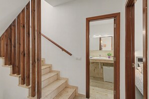 Een trap met houten leuningen die leidt naar een kamer met een badkamer en een bed.