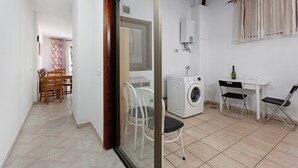 Une pièce équipée d’un lave-linge, d’une table avec des chaises et d’une fenêtre avec des rideaux.