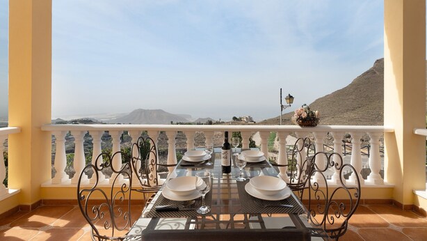 Mesa de comedor preparada para cuatro personas, con vistas a montañas al fondo.
