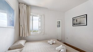 Een kamer met een bed, een raam met gordijnen, een inlijsting foto aan de muur en een spiegel.
