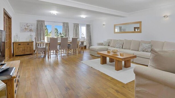 Una sala de estar con sofá, mesa de centro, mesa de comedor, sillas y televisor.