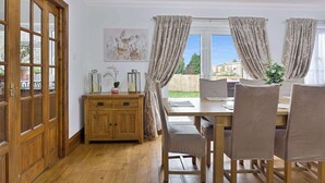 Un comedor con mesa y sillas de madera, un mueble de madera y una ventana con cortinas.