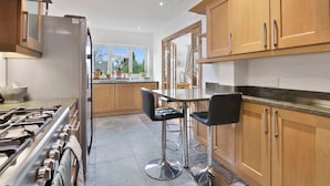 Una cocina moderna con armarios de madera, electrodomésticos de acero inoxidable y una barra con taburetes.