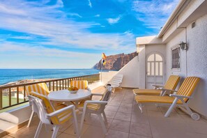 A balcony with a table and chairs, overlooking the sea and a mountainous landscape. - Holiday Apartment "Los Gigantes Sea View" near Beach with Shared Pool & Wi-Fi (Santiago del Teide)