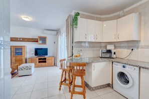 A modern kitchen with a built-in washing machine, a microwave, and a television. - Holiday Apartment "Los Gigantes Sea View" near Beach with Shared Pool & Wi-Fi (Santiago del Teide)