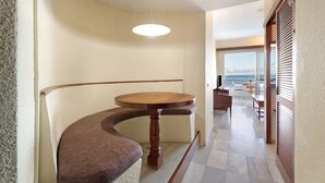 Eine gebogene Bank, ein runder Tisch, eine hängende Leuchte und Blick aufs Meer durch große Fenster.