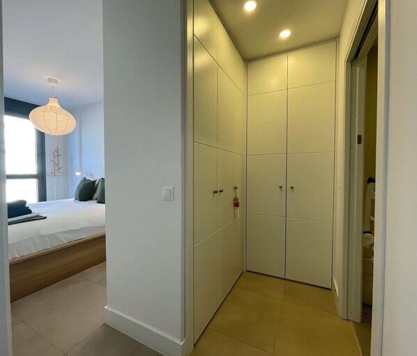 Un dormitorio con cama, mesita de noche y lámpara colgante.