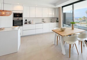 A modern kitchen with white cabinetry, a wooden dining table, and chairs.