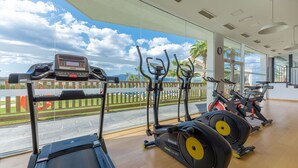 Une salle de sport équipée de matériel d’exercice, dotée de grandes fenêtres et offrant une vue sur l’extérieur.