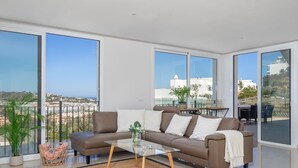 Un salon moderne avec un canapé, une table basse et de grandes fenêtres donnant sur la ville.