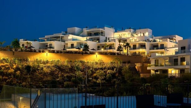 Un hôtel moderne composé de plusieurs bâtiments blancs, doté d’une piscine et d’un espace paysager agrémenté de plantes.