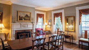 A dining room with a fireplace, a table set for six, and a red armchair. - Historic Home: Game Room & Fire Pit, Near Downtown (Geneva)