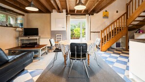Un espace repas comprenant une table, des chaises, un canapé, un téléviseur et un escalier.