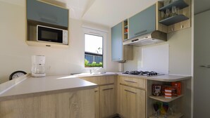 Une cuisine moderne avec des meubles en bois, un four à micro-ondes encastré, une machine à café et une fenêtre.