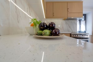 A kitchen with marble countertops, a stove, and cabinets.