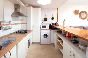 A compact kitchen with a stove, microwave, and washing machine.