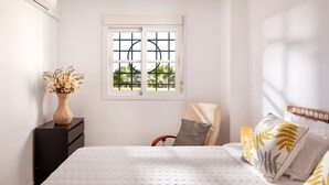 A bedroom with a bed, a chair, a dresser, a window with a view, and an air conditioner.