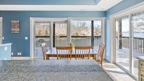 A dining area with a table and chairs, large windows, and a view of the outdoors. - Sleeps 26 lakefront w/ private dock & dance floor! (Lake Ozark)