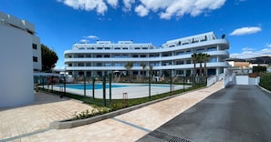 A modern multi-story hotel with a swimming pool, paved walkways, and a clear blue sky. - Apartment 'Sun Garden' with Sea View, Wi-Fi & A/C (Torrox)