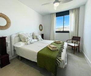 A bedroom with a bed, a chair, a desk, a window with curtains, and a ceiling fan. - Apartment 'Sun Garden' with Sea View, Wi-Fi & A/C (Torrox)