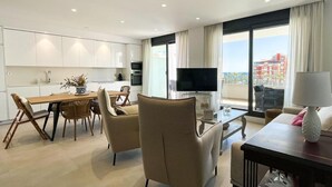 Une chambre d’hôtel moderne dotée d’un coin repas, d’une télévision à écran plat et d’un balcon offrant une vue sur la ville.