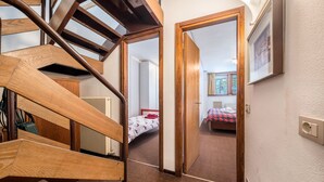 Una escalera de madera que lleva a un dormitorio con cama y ventana.