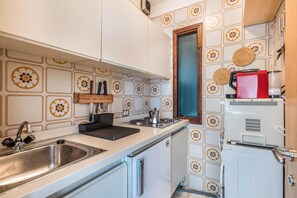 A kitchen with a stainless steel sink, a stove, and a white refrigerator.