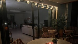 A modern living room with a round table, wicker chairs, and a glass door leading to a kitchen. - Apartment 'Holiday Apartment Middle Views' with Sea View, Wi-Fi and Air Conditioning (FUENGIROLA)