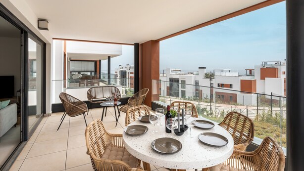 A balcony with a round table set for dining, wicker chairs, and a city view. - Apartment 'Holiday Apartment Middle Views' with Sea View, Wi-Fi and Air Conditioning (FUENGIROLA)