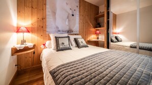 Une chambre avec une grande affiche représentant un ours polaire, des murs recouverts de panneaux de bois, un lit avec une couverture matelassée, des lampes de chevet et un miroir.