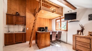 Un interior de madera con cocina, comedor y televisor montado en la pared.