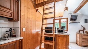 Cocina de madera con escalera empotrada, un microondas y un televisor en un estante.