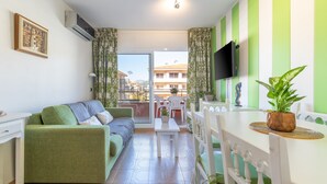 A modern living room with a sofa, a dining table, and a TV. - Apartment 'Salines' with Shared Pool, Balcony and Air Conditioning (Estartit)