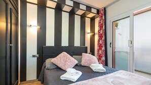 A hotel room with a bed, pillows, a bedside table, a wardrobe, and a sliding glass door. - Apartment 'Salines' with Shared Pool, Balcony and Air Conditioning (Estartit)