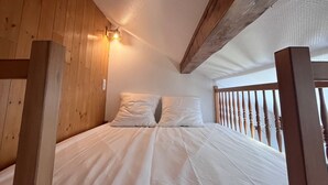 A bedroom with a wooden ceiling, a bed with white bedding, and a wooden railing. - Studio 'Au Rêve Savoyard 7' with Mountain View, for 4 People (Morillon)