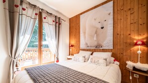 A bedroom with a large bed, wooden walls, a window with curtains, a wall-mounted polar bear picture, and a bedside lamp. - Apartment "Au Rêve Savoyard 5" with Mountain View for 4 People (Morillon)